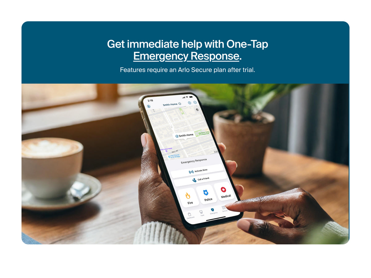 Promotional graphic for Arlo Secure app, showing a person holding a smartphone with the app interface displayed on the screen, with a coffee cup and potted plant in the background. A dark blue banner at the top reads: 'Get immediate help with One-Tap Emergency Response.