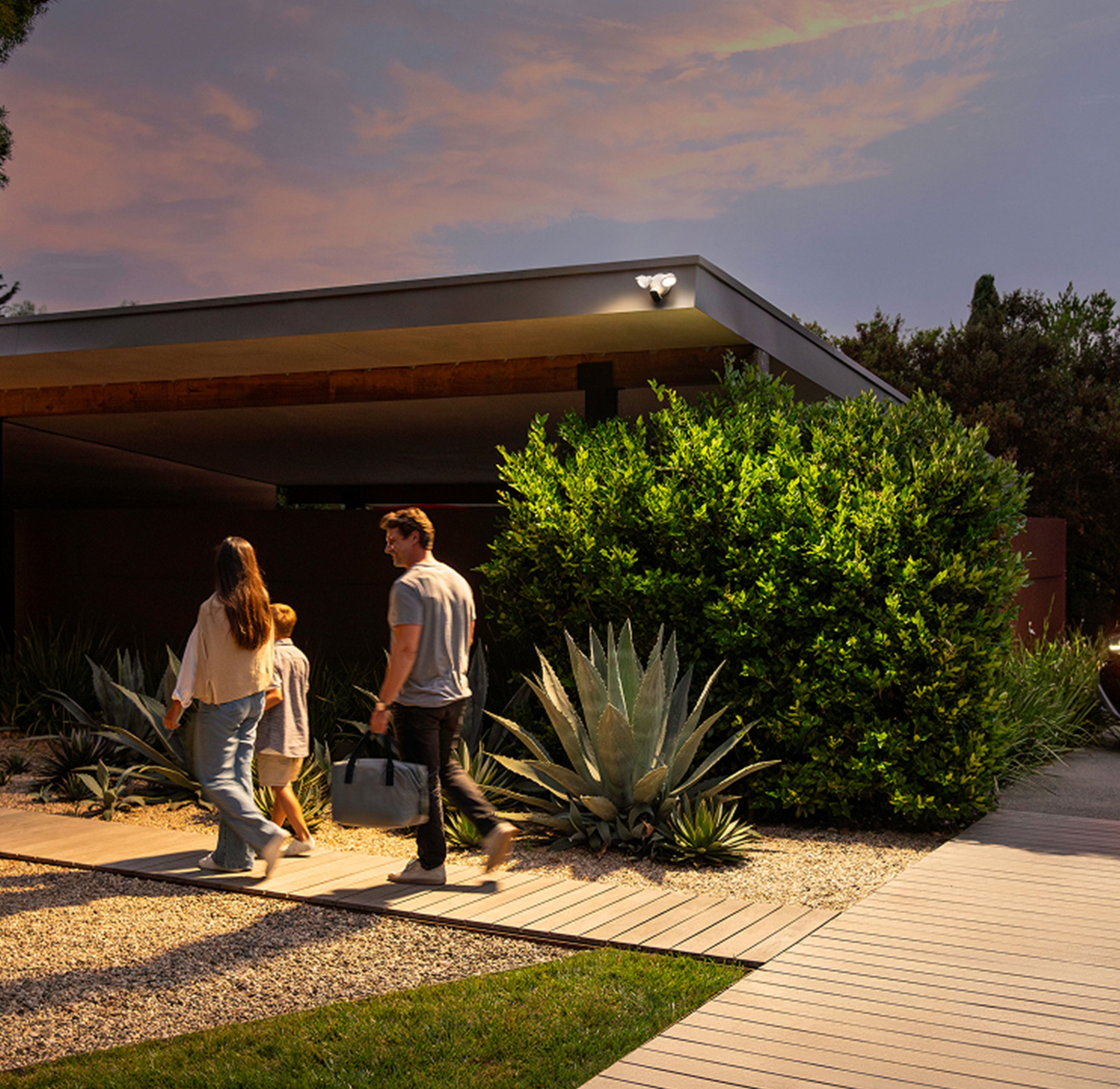 A family walking in front of a house with the Arlo Wired Floodlight