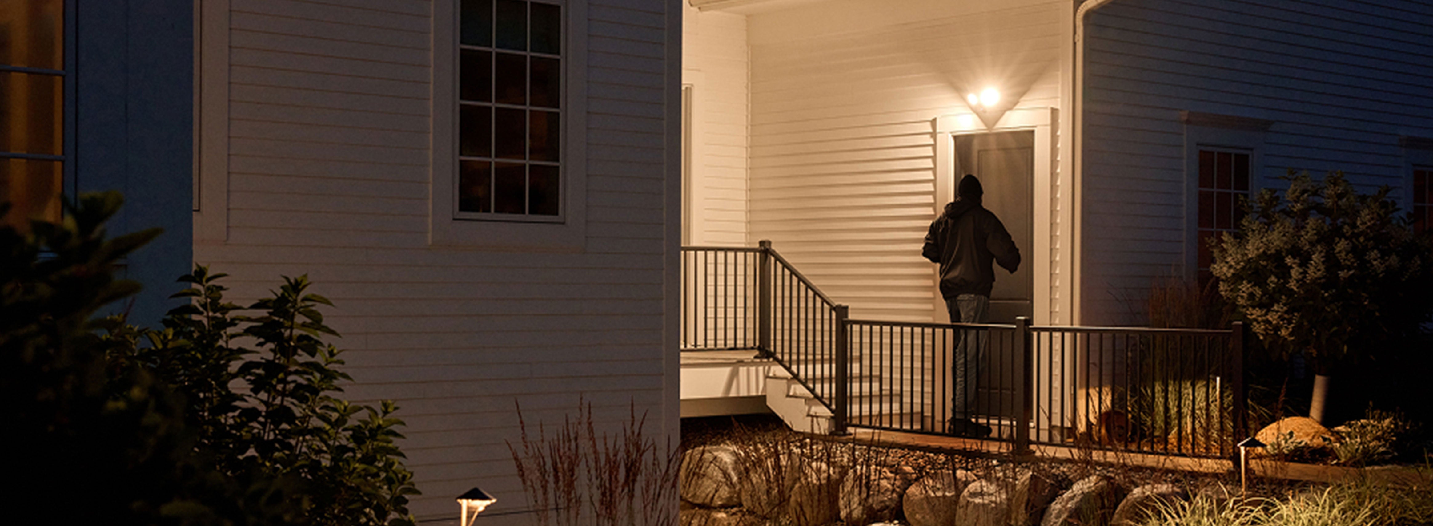 A burglary trying to enter a door with the Arlo Wired Floodlight shining a light