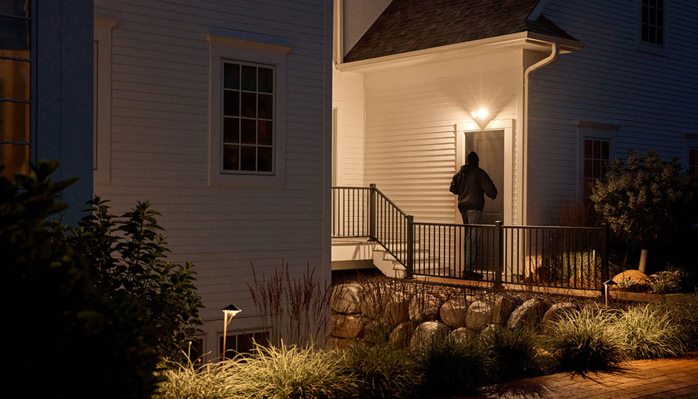 A burglary trying to enter a door with the Arlo Wired Floodlight shining a light